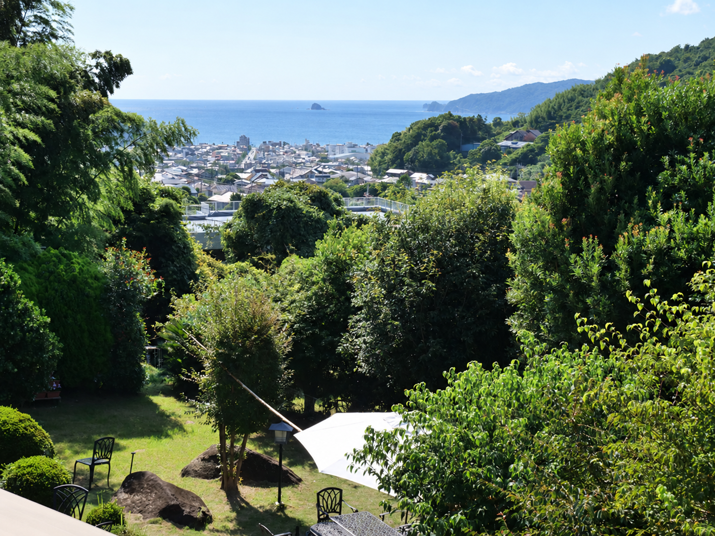 丘の上の約700坪の敷地。庭木と芝生の向こうに相模湾と伊東市宇佐美の街並みが見える